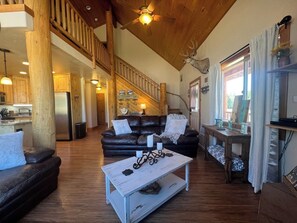 A spacious living area with a wooden staircase, a black leather sofa, a white coffee table, and a mounted deer head. - Brian Head Ski Ranch minutes to Ski Slopes-3/3bath (Brian Head)