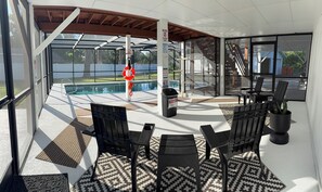 An outdoor patio area with a pool, black chairs, a potted plant, and a lifebuoy.