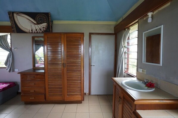 A room with a wooden wardrobe, a mirror, a sink, and a door. - Safe Landing Eco Lodge  (Nacula Island)