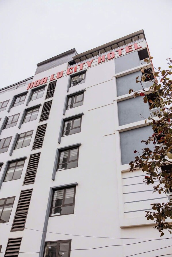 Un immeuble à plusieurs étages, sur lequel on peut lire l’inscription « HOOLU CITY HOTEL » en haut.