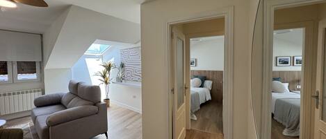 Un loft moderno con techos altos, tragaluces, un sofá gris y piso de madera.