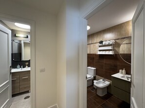Une salle de bain moderne équipée d’un meuble-lavabo, de toilettes, d’un bidet et d’un porte-serviettes.