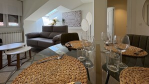 Ein modernes Wohnzimmer mit einer Couch, einem Esstisch mit Gläsern und einem Deckenventilator.