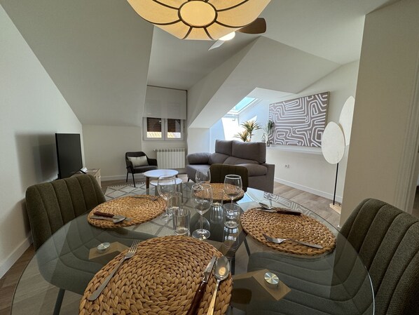 Un espace repas moderne avec une table en verre, des sets de table en fibres tressées et un luminaire au design contemporain.