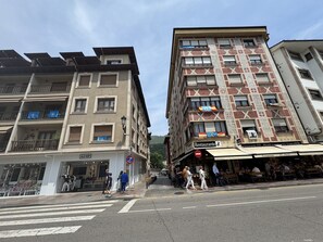 Une vue de rue avec un immeuble doté de balcons, une enseigne de restaurant et un passage piéton.