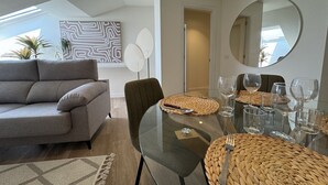 Ein modernes Wohnzimmer mit einem Glastisch, einem grauen Sofa und einem grünen Sessel.