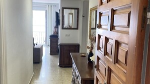 Un pasillo con una puerta de madera, un espejo y un aparador.
