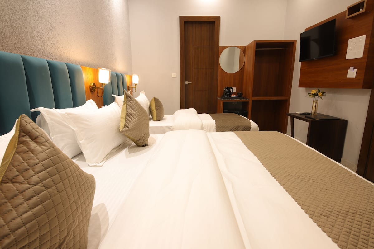 Ein Hotelzimmer mit einem großen Bett, einem Holzschrank, einem Fernseher und einem kleinen Tisch mit einer Vase.