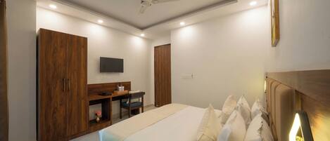 A bedroom with a bed, a desk, and a wardrobe.