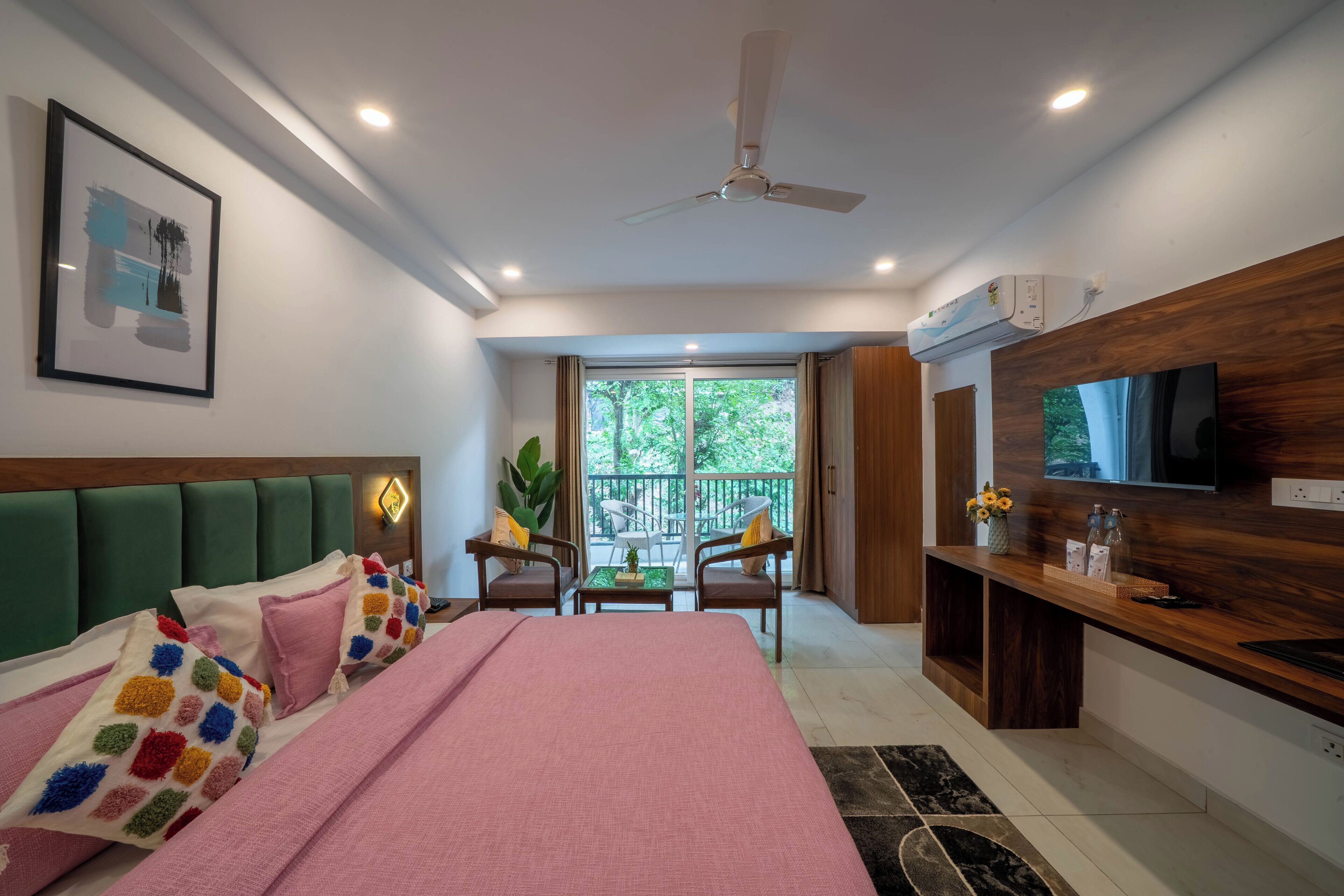 A modern bedroom with a bed, a TV, and a balcony with a view.