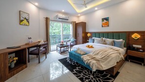 Un dormitorio moderno con cama, escritorio y silla, un balcón con cortinas y obras de arte en las paredes.
