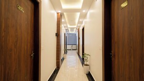 Un pasillo con puertas de madera, piso de mármol y plantas en macetas.