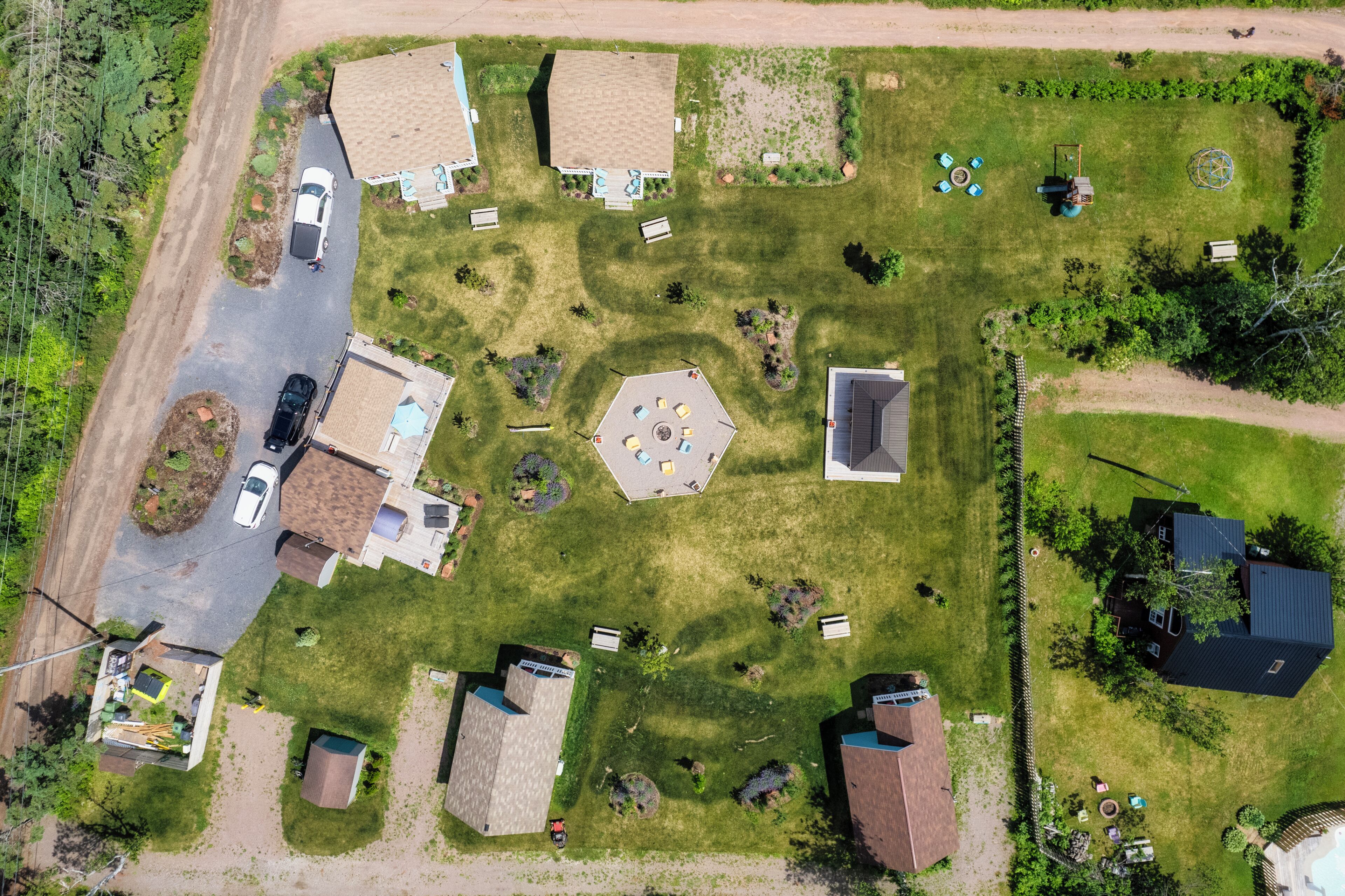 Vue aérienne d’un quartier résidentiel comprenant plusieurs maisons, une structure centrale à huit côtés et une piscine.