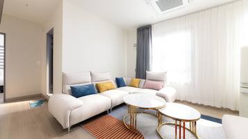 A modern living room with a sectional sofa, two round coffee tables, and a large window with curtains.