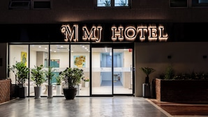 Het uiterlijk van Hotel MJ met een moderne entree, plantenbakken en een bakstenen muur.