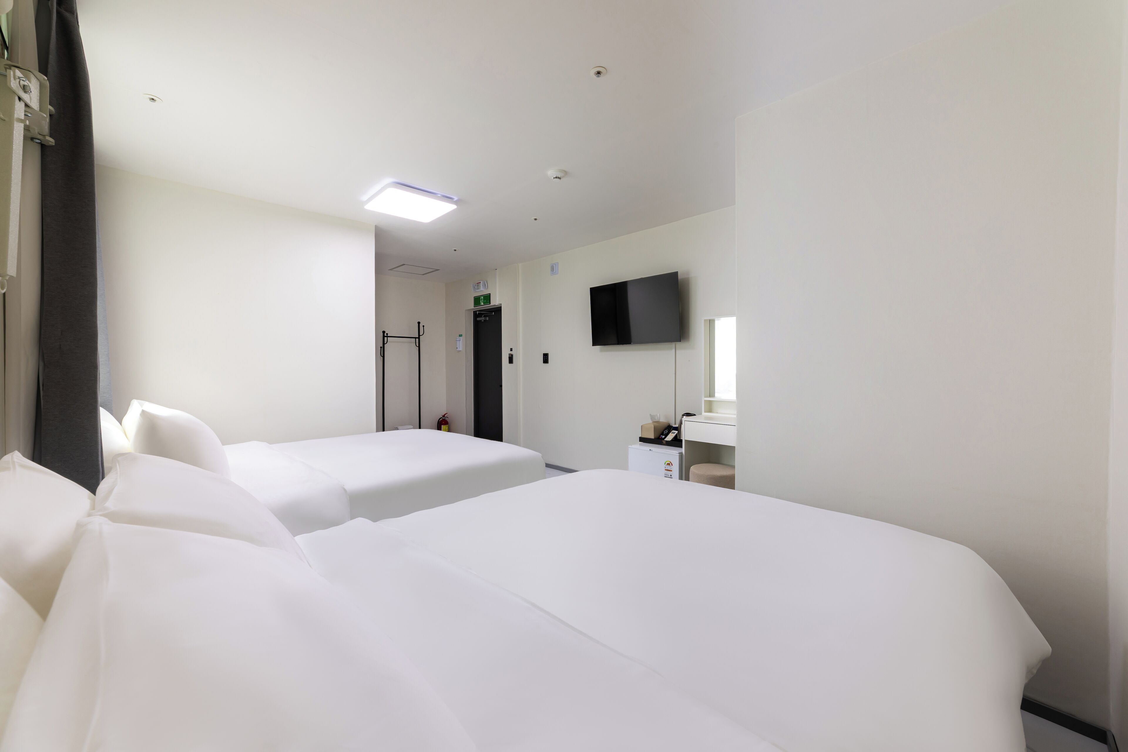 Une chambre d’hôtel avec deux lits, une télévision, un petit bureau et un miroir.