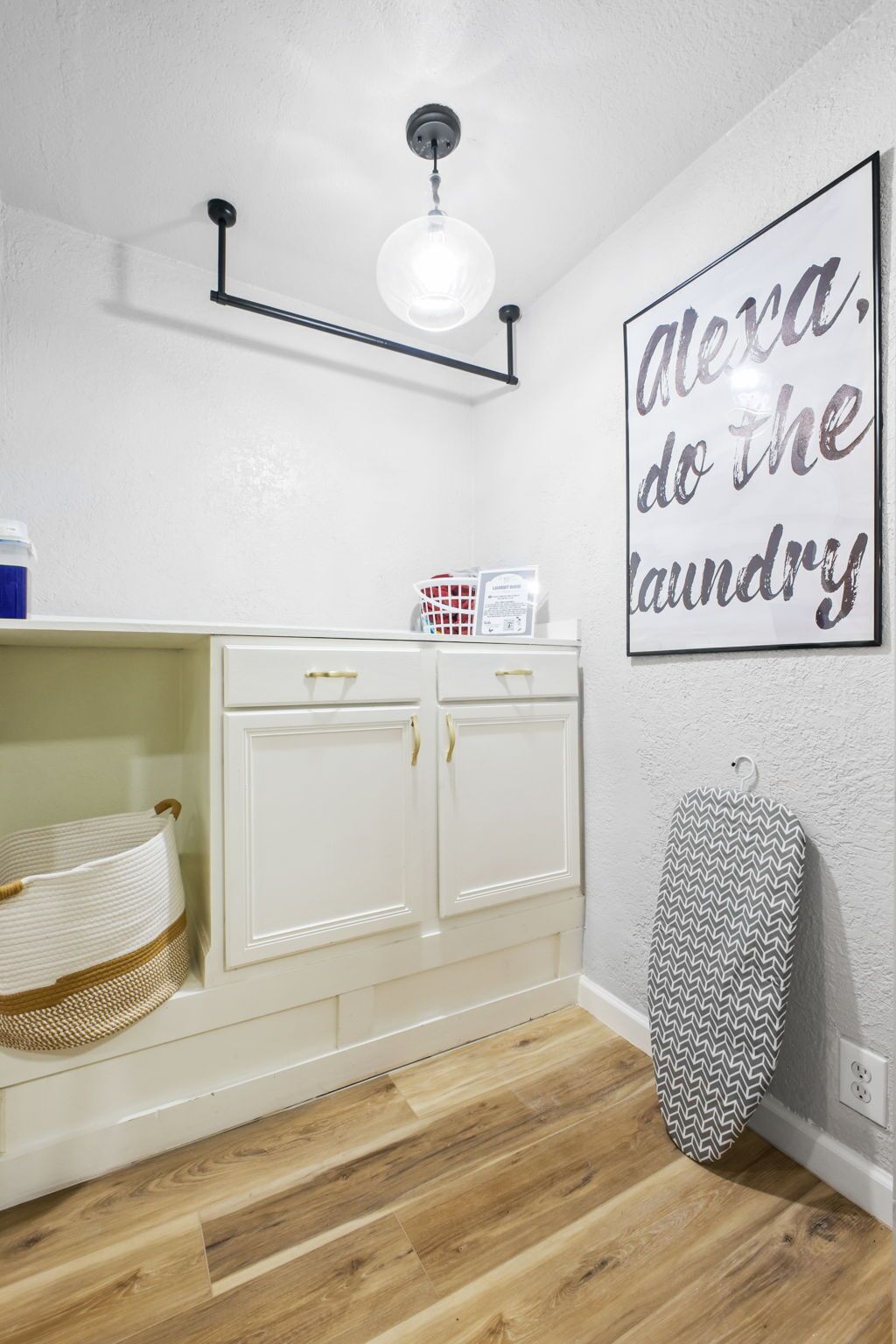 A laundry room with a white cabinet, a hanging iron, and a wall-mounted light fixture.