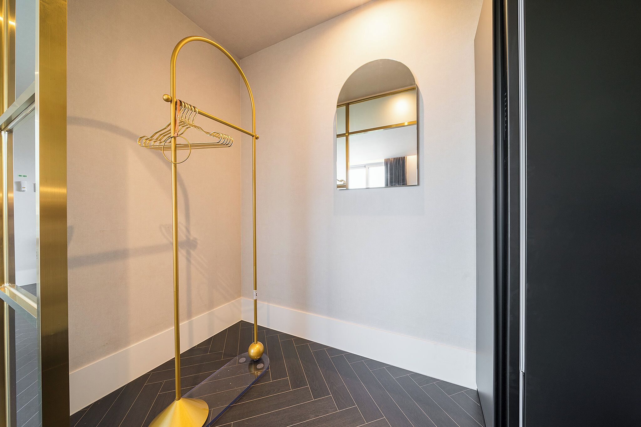 Un baño moderno con un toallero dorado, un espejo y un suelo con diseño oscuro.