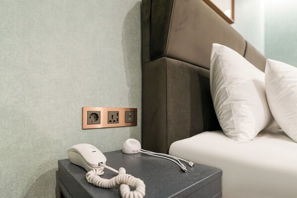 Une chambre d’hôtel équipée d’un téléphone sur la table de chevet, d’une prise de courant et d’une prise murale.