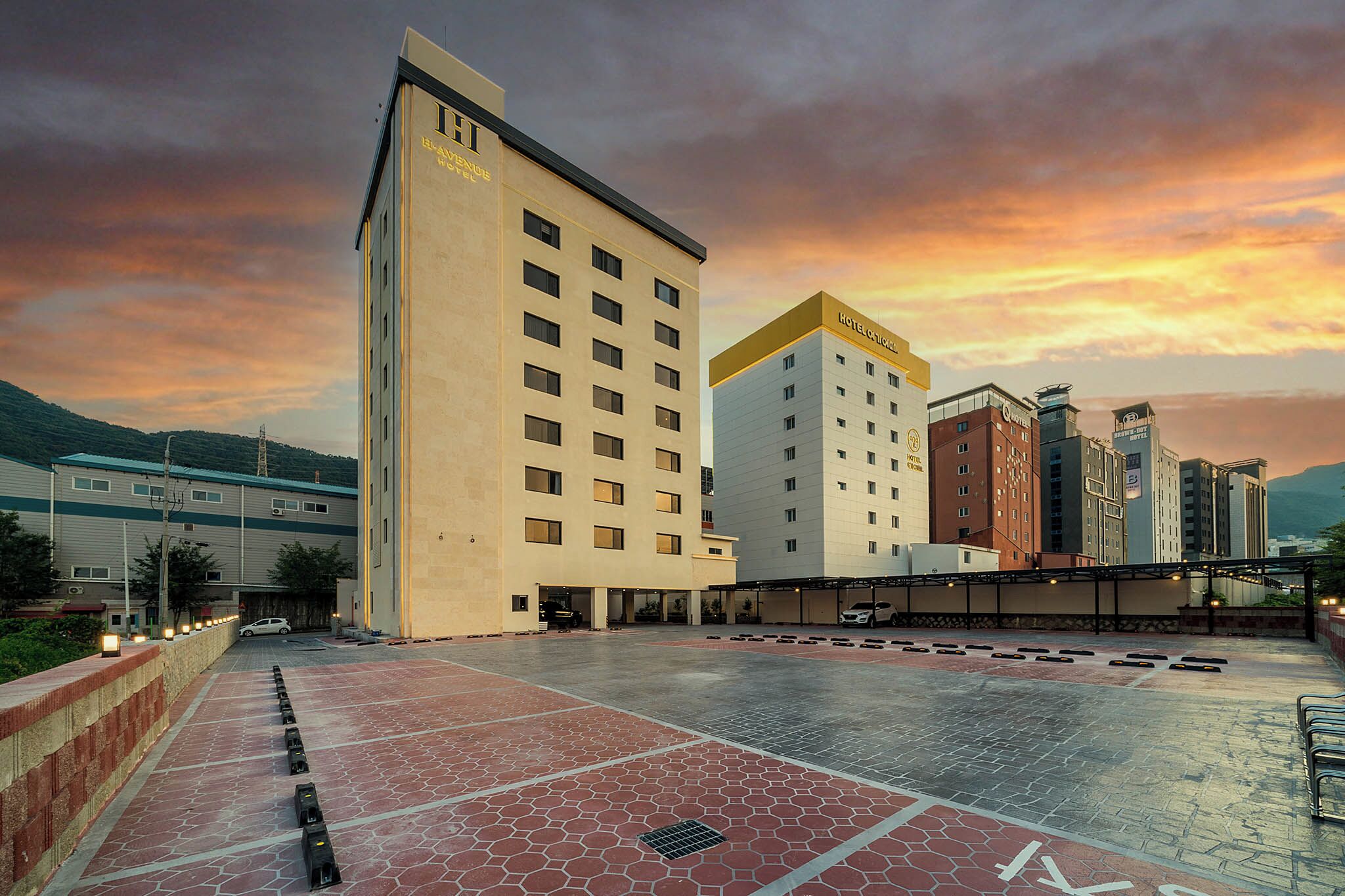 Un hotel con varias edificaciones, un patio empedrado y un cielo al atardecer.