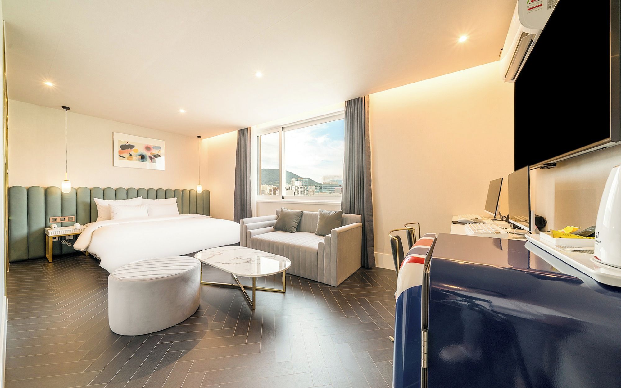Una habitación de hotel con cama, escritorio, silla, una mesita y un sofá.