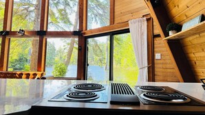 Una cocina con ventanas amplias, una estufa y vistas a árboles.