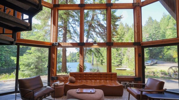 Una habitación amplia con ventanas grandes, un sofá de cuero y dos sillones de cuero.