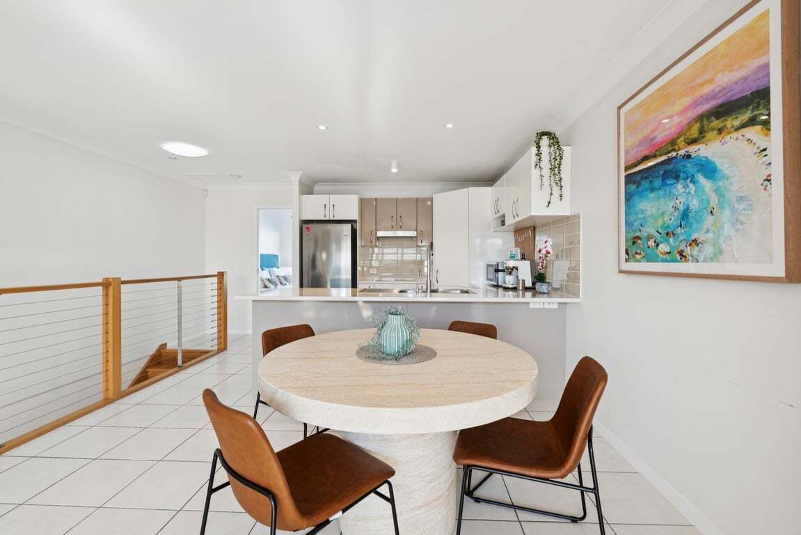 A modern kitchen with white cabinets, a stainless steel refrigerator, and a hanging plant.