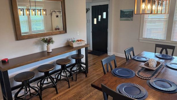 A dining area with a wooden table set for four, black chairs, and a mirror above the table. - Big Country Escape - 4 Bedroom, Pet Friendly Retreat in Bluewell,  Near Trails (Bluefield)