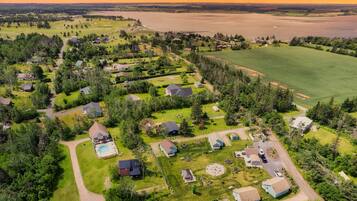 Une vue aérienne d’un quartier résidentiel avec des maisons, une piscine et une grande étendue d’eau en arrière-plan.
