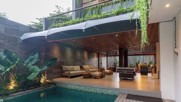 Un área de piscina interior moderna con terraza de madera, asientos de descanso y mesa de billar.