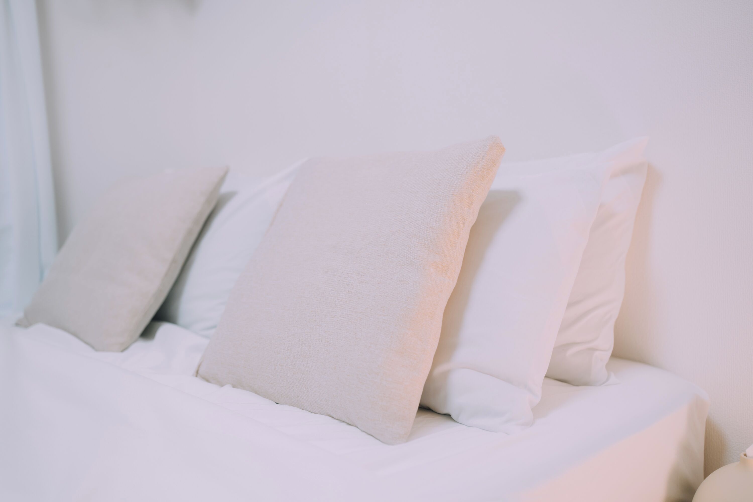 Una cama con ropa de cama y almohadas blancas.