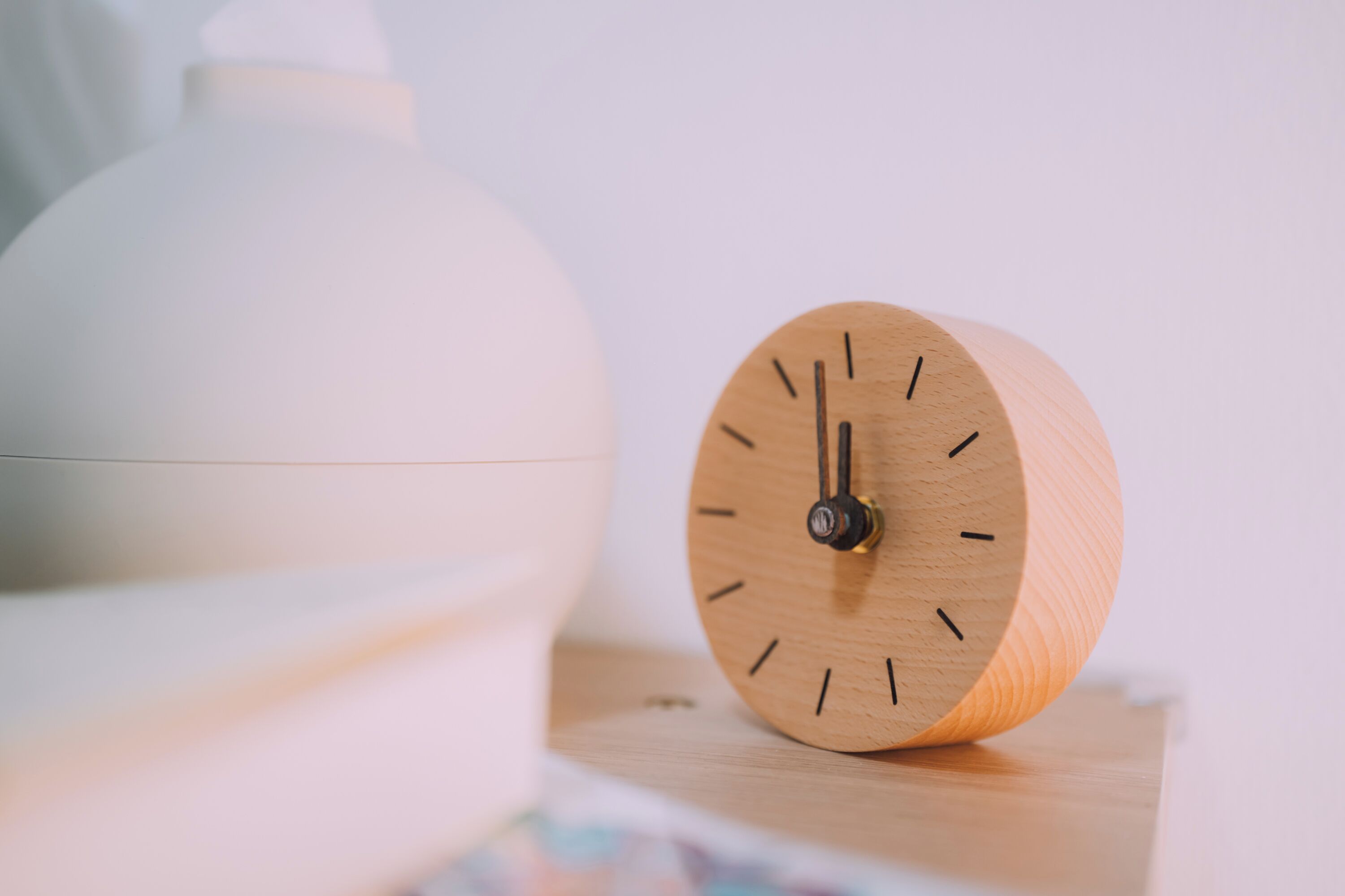 A wooden clock with a minimalist design on a wooden surface.