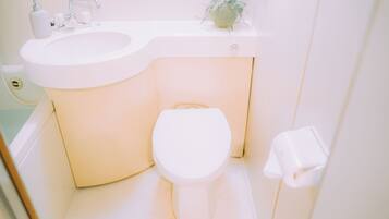 A white bathroom with a sink, toilet, and a small potted plant on the countertop.