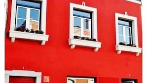 Un edificio rojo con tres ventanas y una puerta roja.
