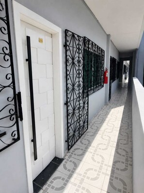 A corridor with a white door, a black metal gate, and a fire extinguisher on the wall.