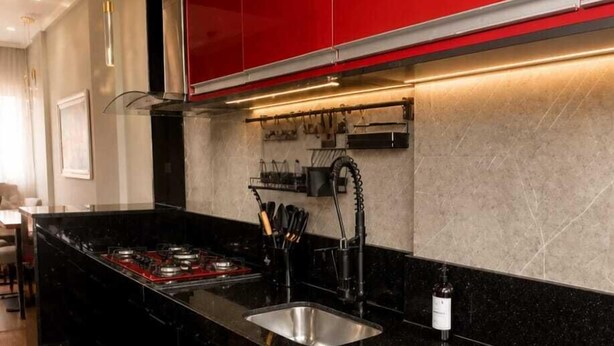 A modern kitchen with red cabinets, a black countertop, and a stainless steel sink. - Feel at Home in Belém – Cozy & Fully Equipped Apartment in Guamá (Guamá, Belém)