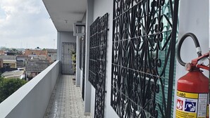 A balcony with patterned floor tiles, a metal decorative wall, and a fire extinguisher. - Feel at Home in Belém – Cozy & Fully Equipped Apartment in Guamá (Guamá, Belém)