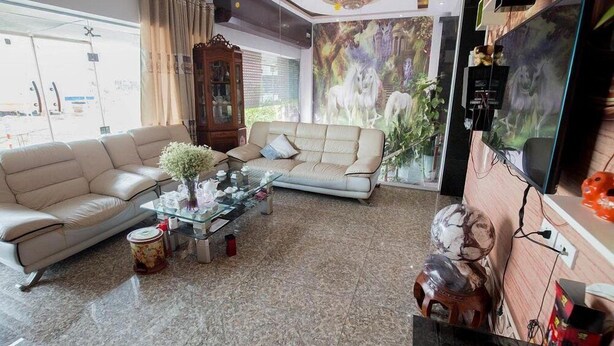 A living room with a beige sofa, a glass coffee table, and a decorative vase. - An Binh 2 Hotel BG - by BAY LUXURY (Bac Giang)