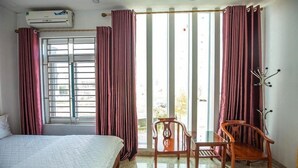 A hotel room with a bed, a chair, a table, and a window with curtains. - An Binh 2 Hotel BG - by BAY LUXURY (Bac Giang)