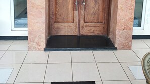 Una coppia di porte in legno con stipite in marmo, soglia nera e pavimento piastrellato.