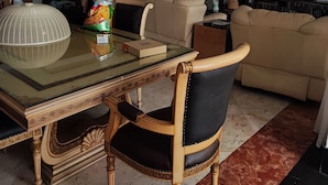 Zona pranzo con tavolo in vetro, sedie in legno e una lampada decorativa.