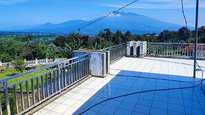Una terrazza piastrellata con ringhiera metallica che si affaccia su un paesaggio montuoso.