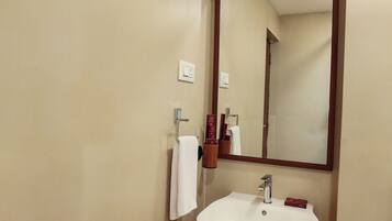 A bathroom with a white sink, a mirror, and a black trash bin.