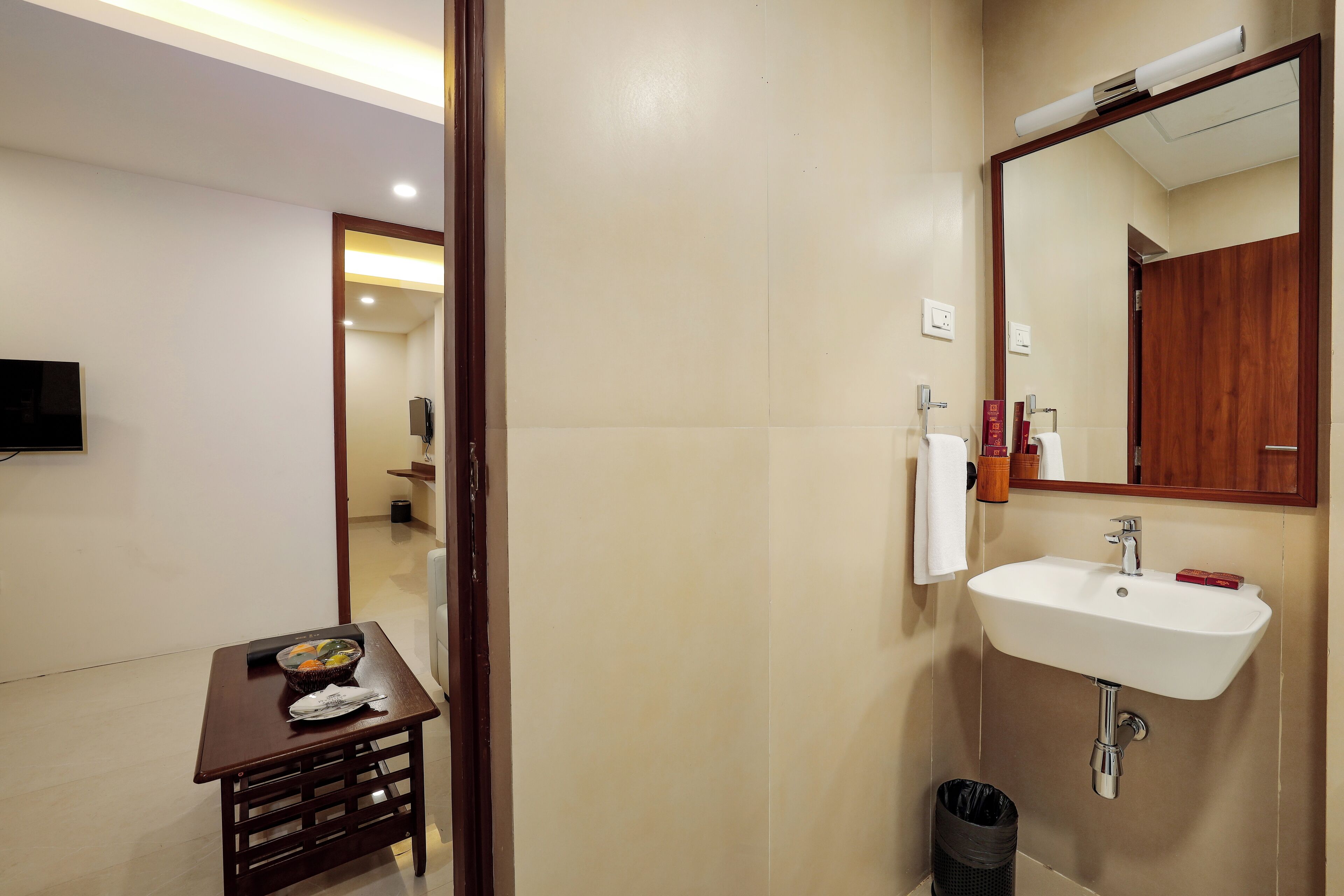A bathroom with a sink, mirror, and a small table with a bowl and napkins.