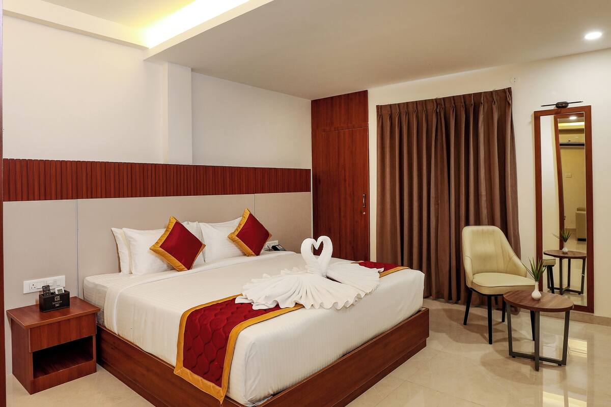 Ein Hotelzimmer mit einem großen Bett, einem Nachttisch, einem Sessel, einem kleinen Tisch und einem Spiegel.