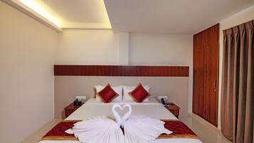 A hotel room with a neatly made bed, a wooden headboard, a bedside table with a phone, and a wardrobe.