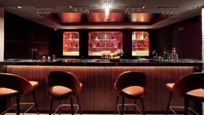 A bar area with a counter, three shelves of bottles, and four bar stools. - Sathyam Oasis  (Tiruchirappalli)