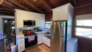 Una cocina moderna con gabinetes blancos, electrodomésticos de acero inoxidable y techo de madera.