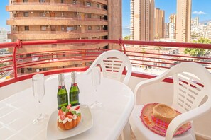 Een balkon met een tafel gedekt voor twee personen, inclusief een dessert, twee champagneflessen en twee glazen.